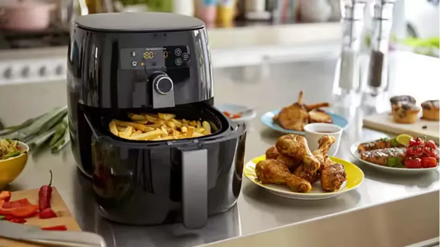 Air fryer basket with fries and wings ready to cook
