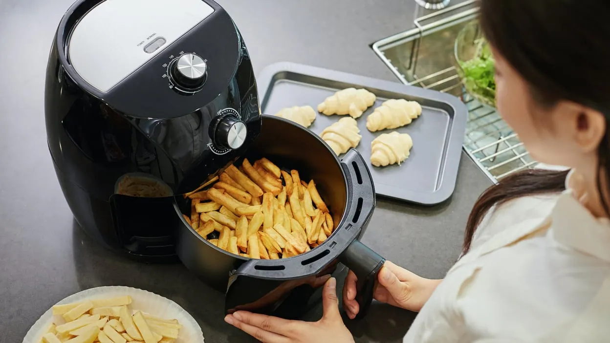 Overfilled air fryer basket spilling fries on countertop